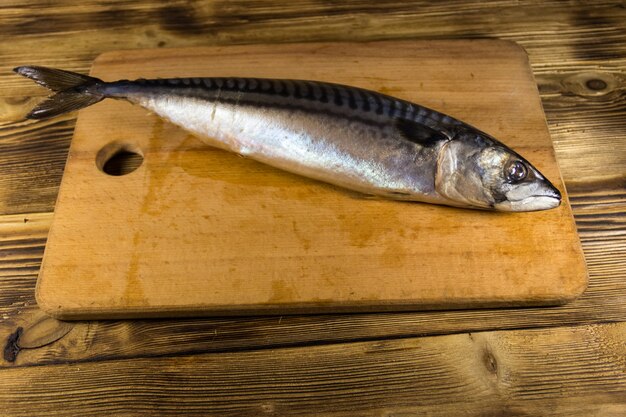 Pescado scomber salado sobre tabla de cortar. Caballa entera sobre mesa de madera