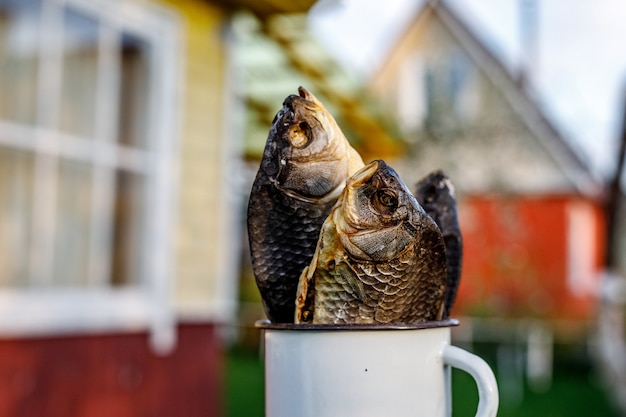 Pescado seco en una taza blanca con un fondo de casa de campo.