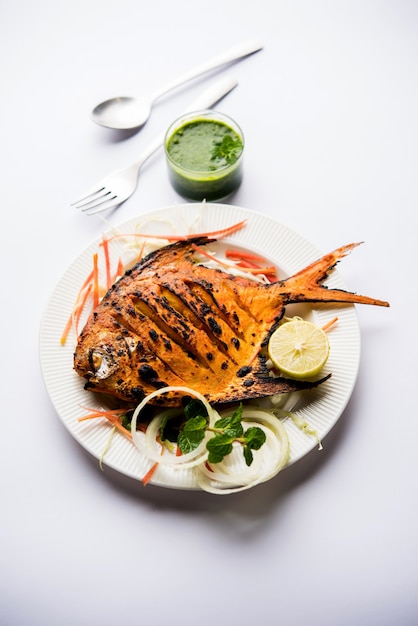 Pescado Tandoori Pomfret cocido en horno de barro y aderezado con ensalada de limón, menta, repollo y zanahoria