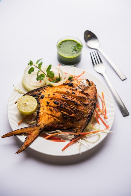 Pescado Tandoori Pomfret cocido en horno de barro y aderezado con ensalada de limón, menta, repollo y zanahoria