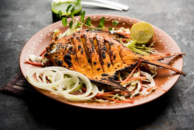 Pescado Tandoori Pomfret cocido en horno de barro y aderezado con ensalada de limón, menta, repollo y zanahoria