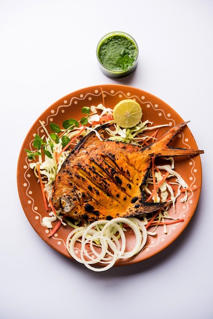 Pescado Tandoori Pomfret cocido en horno de barro y aderezado con ensalada de limón, menta, repollo y zanahoria