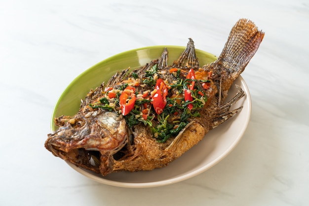 Pescado tilapia frito con salsa de ajo y albahaca encima