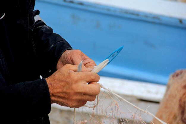 Foto pescador a reparar redes de pesca