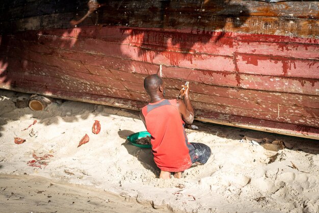 Pescador africano na praia consertando seu barco