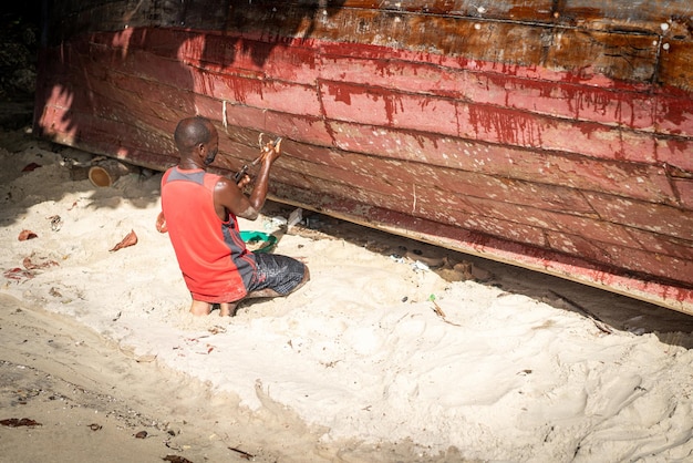 Pescador africano en la playa reparando su barco