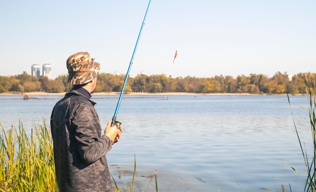 Un pescador arrojó una caña giratoria a un lago o río en un día soleado Pesca desde la costa Un pescador
