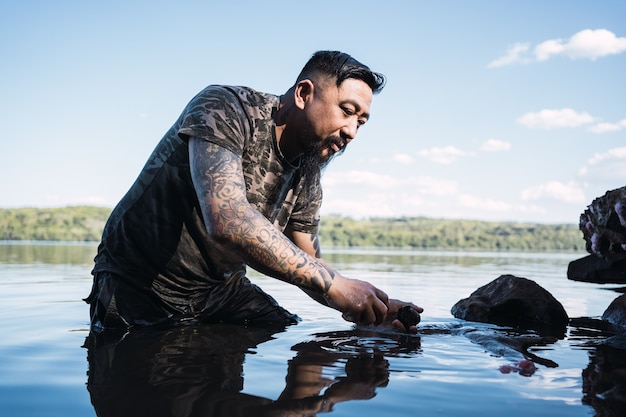 Pescador asiático recogiendo caracoles para pescar