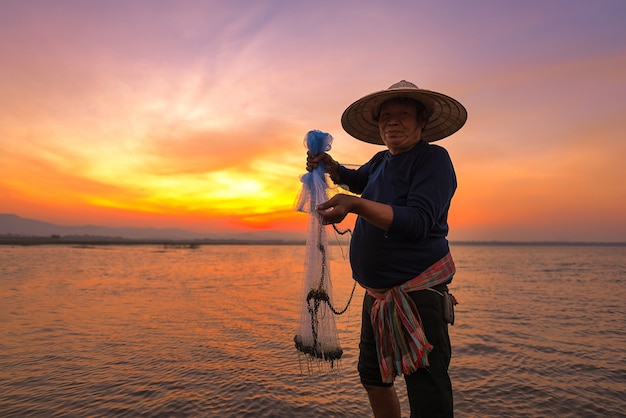 Pescador asiático en el río de la naturaleza en la madrugada antes del amanecer