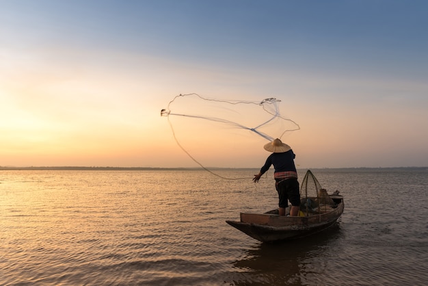 Pescador asiático con su barco de madera en el río de la naturaleza en la madrugada antes del amanecer