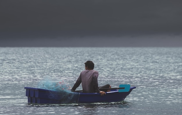 Pescador asiático trabajando en bote pequeño