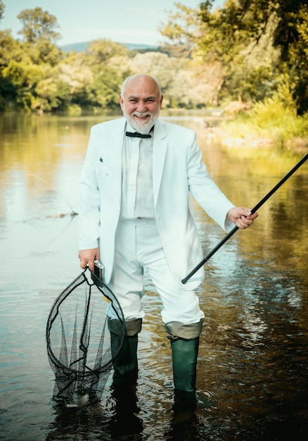 Pescador barbudo na água, homem sênior pescando no lago, pescador feliz pescador longo