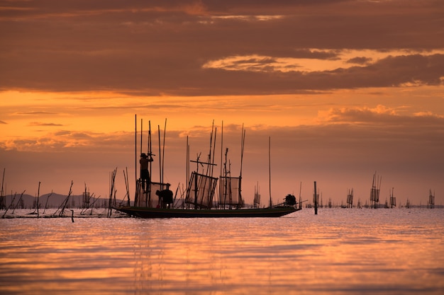 Pescador en el barco de captura de peces con puesta de sol