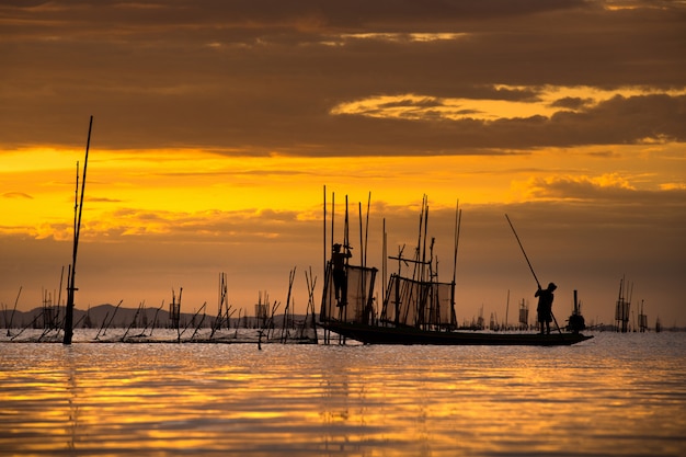Pescador en el barco de captura de peces con salida del sol