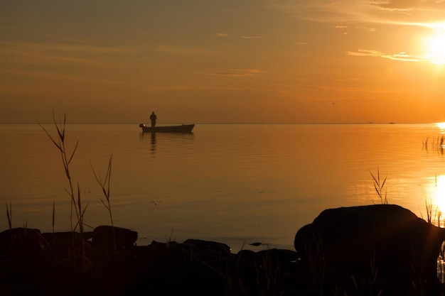 Pescador en el barco en el mar dorado del atardecer hermosa y romántica puesta de sol silueta de pescadores con su barco