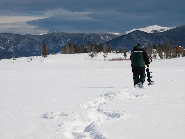 Pescador con una barrena en el lago congelado Granby, Colorado.