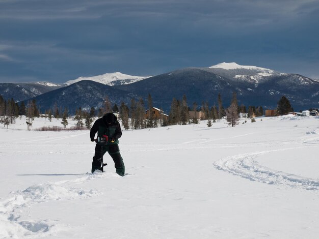 Pescador con una barrena en el lago congelado Granby, Colorado.