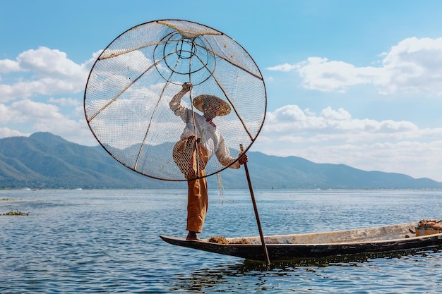 Pescador birmano en un bote con una red hecha a mano. Lago Inle, Birmania