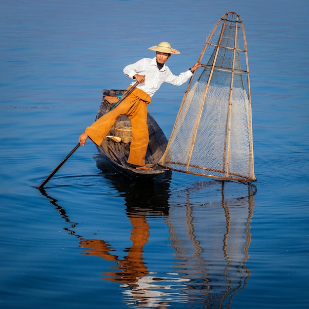 Foto pescador birmano tradicional con una red de pesca en el lago inle en myanmar