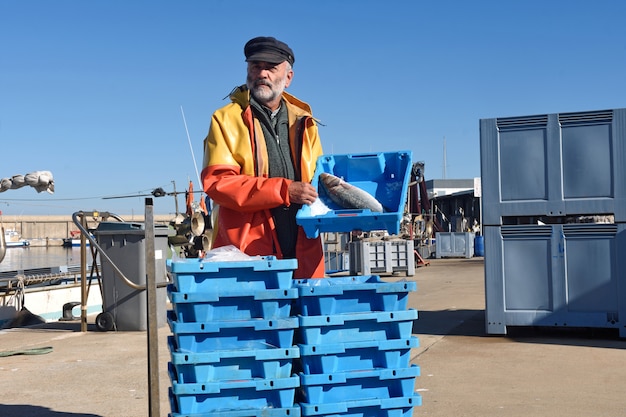 Pescador con una caja de peces dentro de un barco de pesca