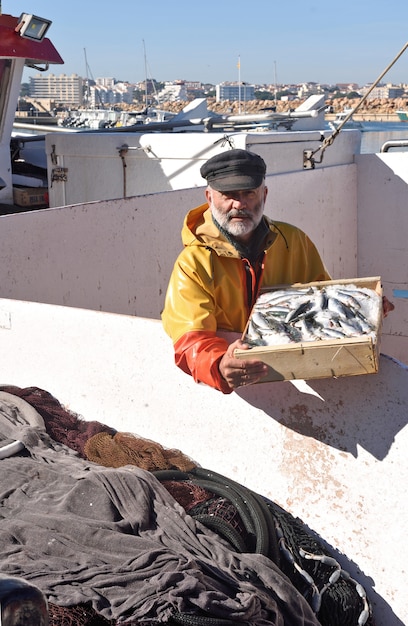 Pescador con una caja de peces dentro de un barco de pesca