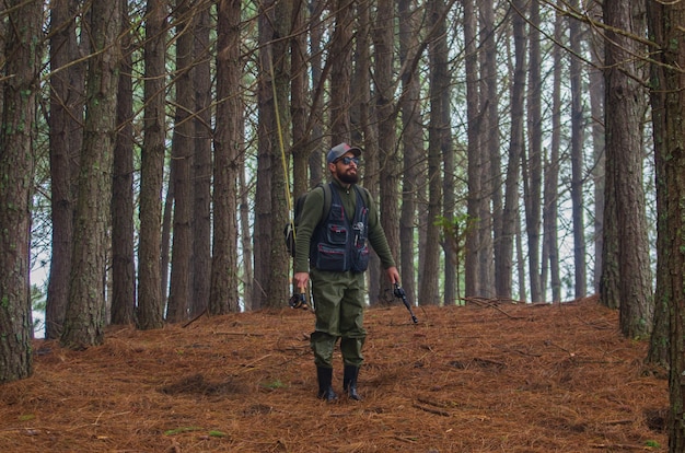 Foto pescador caminando en el bosque de pinos