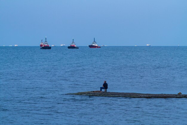 Pescador con caña de pescar captura peces cerca del puerto marítimo comercial de Novorossiysk