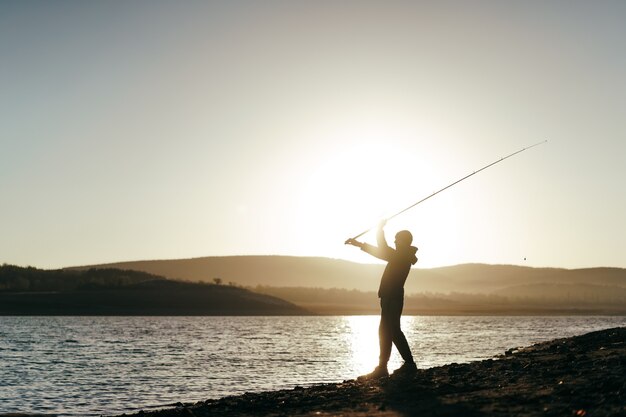 Pescador con caña de pescar en el lago