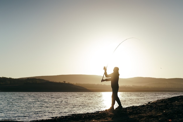 Foto pescador con caña de pescar en el lago