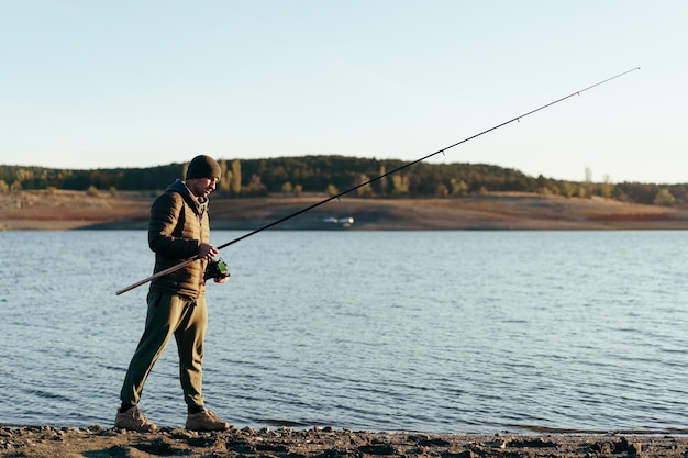 Pescador con caña de pescar en el lago