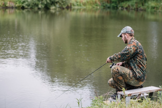 Un pescador con una caña de pescar en la orilla del río.