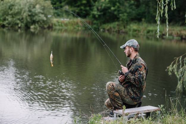 Un pescador con una caña de pescar en la orilla del río.