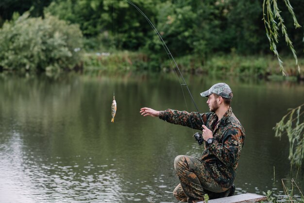 Un pescador con una caña de pescar en la orilla del río.