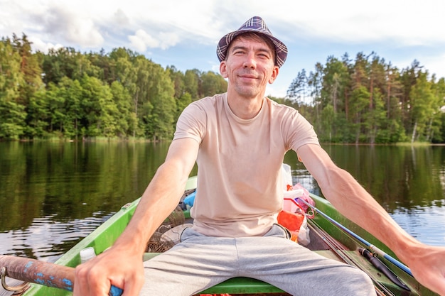 Pescador con cañas de pescar está pescando en un bote de goma en el lago o río