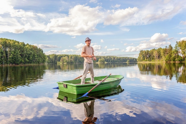 Pescador con cañas de pescar está pescando en un bote de madera en el lago o río