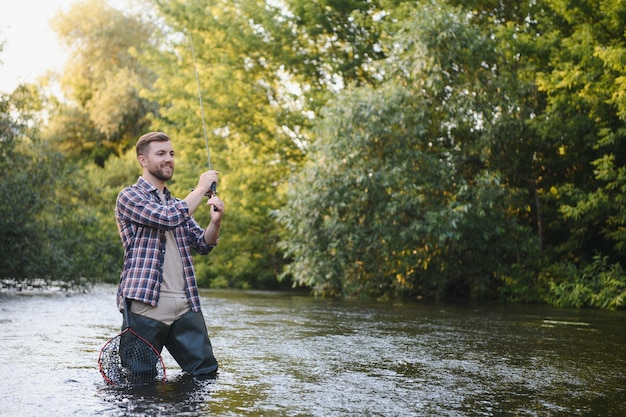 Foto el pescador coge una trucha en el río en verano