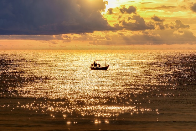 Pescador com barco de pesca navegando no mar dourado pela manhã