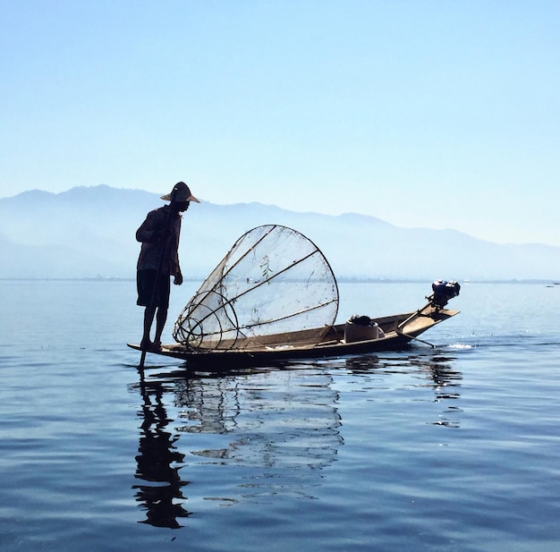 Pescador com rede de pesca em um barco em um lago