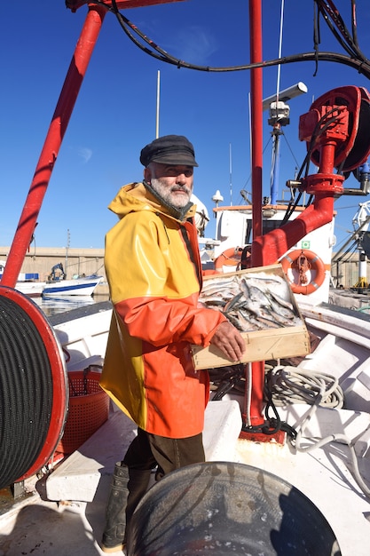 Pescador com uma caixa de peixe dentro de um barco de pesca