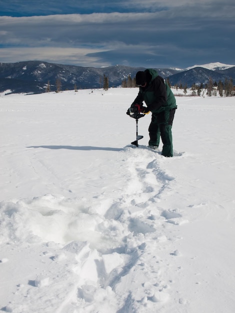 Pescador com uma verruma no lago congelado Granby, Colorado.