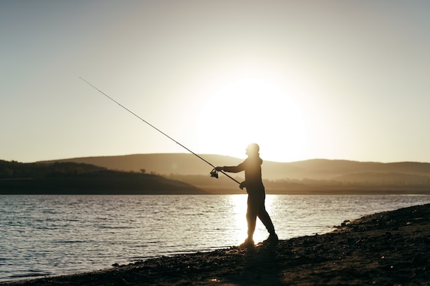 Pescador com vara de pescar no lago