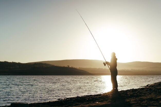 Pescador com vara de pescar no lago