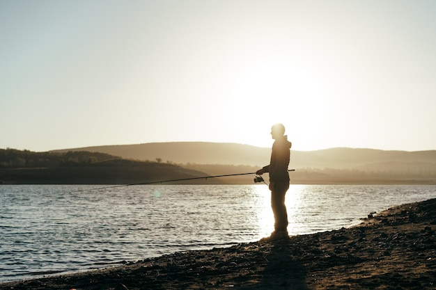 Pescador com vara de pescar no lago