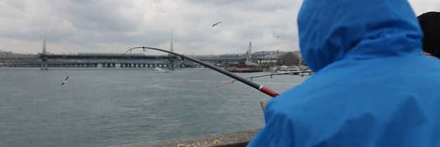 Pescador de manto azul fica de costas e pega peixes com o conceito de hobby de pesca de isca