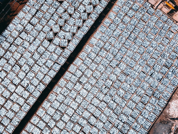 Pescador de vista superior na vila de pescadores Eles estavam secando peixe fresco em uma grade de madeira para o mercado Peixe de arenque de escala azul seco tradicional secando em prateleiras Conceito de estilo de vida