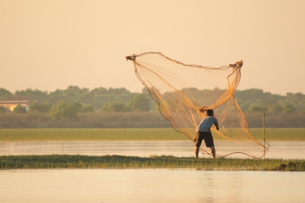 Pescador echando una red en el lago