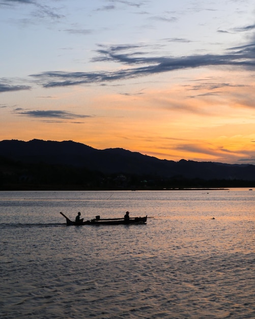 Pescador em seu barco ao pôr do sol. Barco de pescadores ao pôr do sol