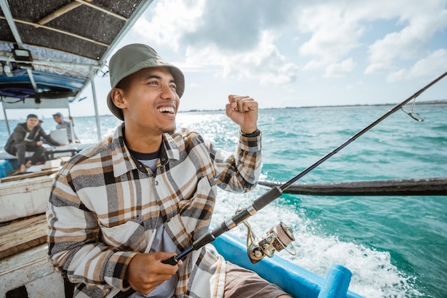 Pescador emocionado con las manos apretadas mientras pesca en el mar