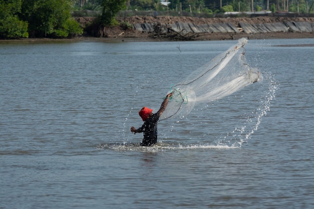 pescador irreconhecível da costa distante jogando rede de pesca para capturar peixes