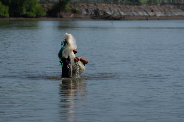 pescador irreconhecível da costa distante jogando rede de pesca para capturar peixes